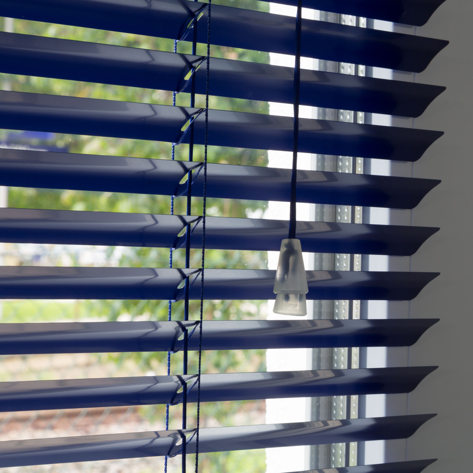 Aluminium Jalousie mit Lamellen und Zugkordel vor einem Fenster
