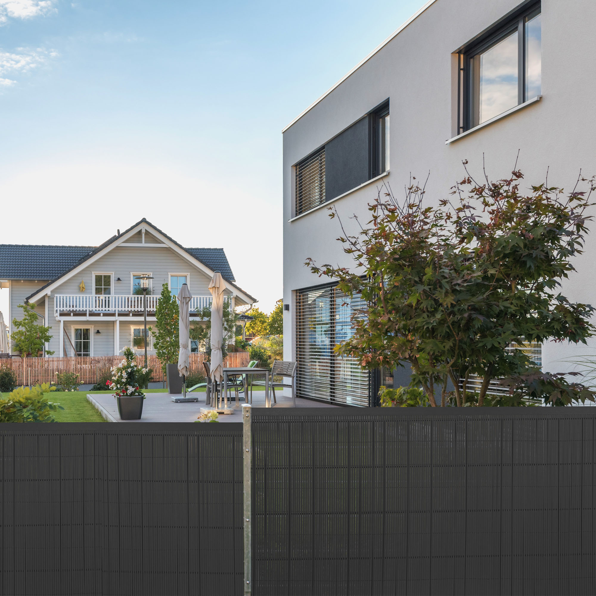 Abdeckprofil für Sichtschutzmatte vor modernem Haus und Garten im Hintergrund