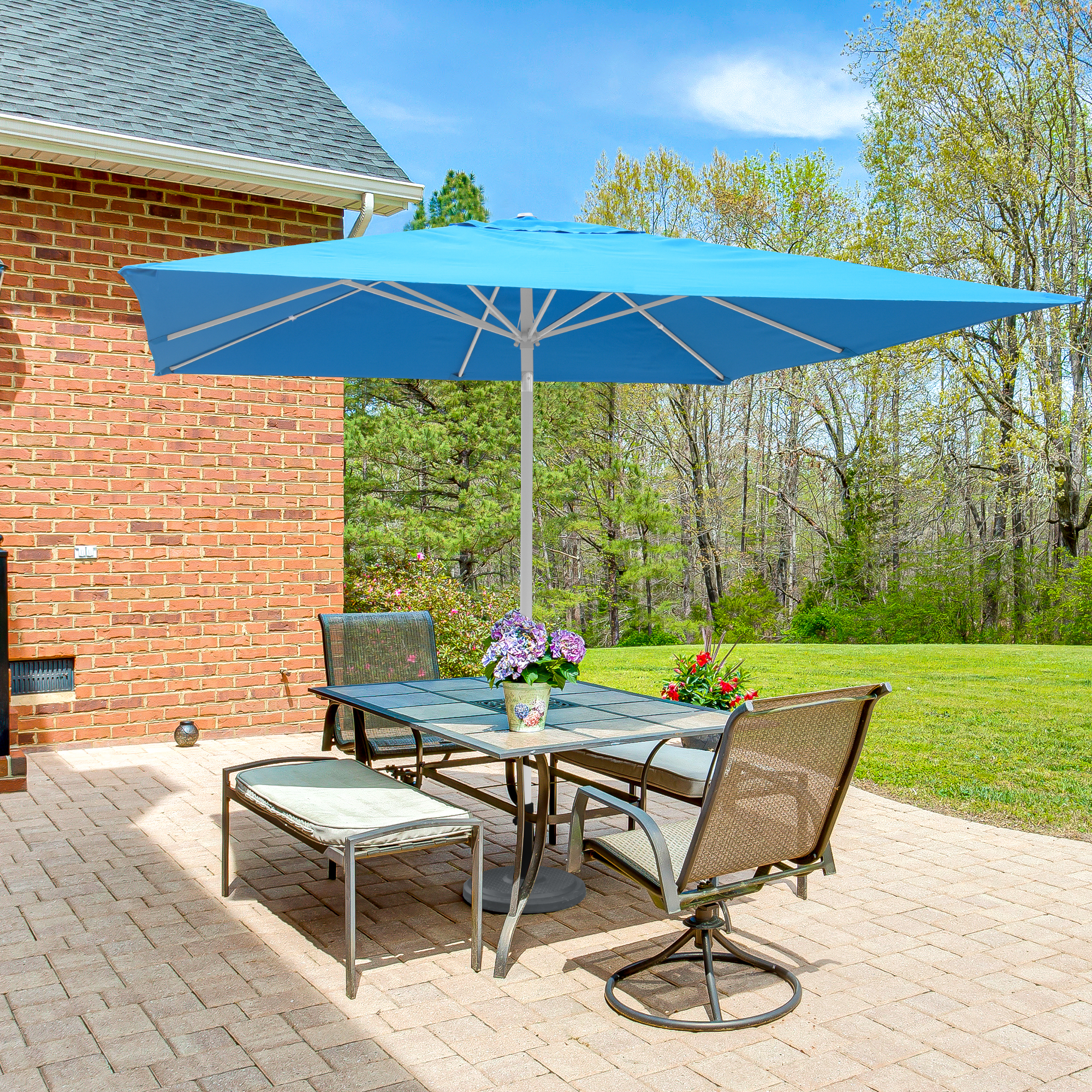 Terrasse mit Tisch, Stühlen und Sonnenschirm auf Schirmständer im Gartenumfeld