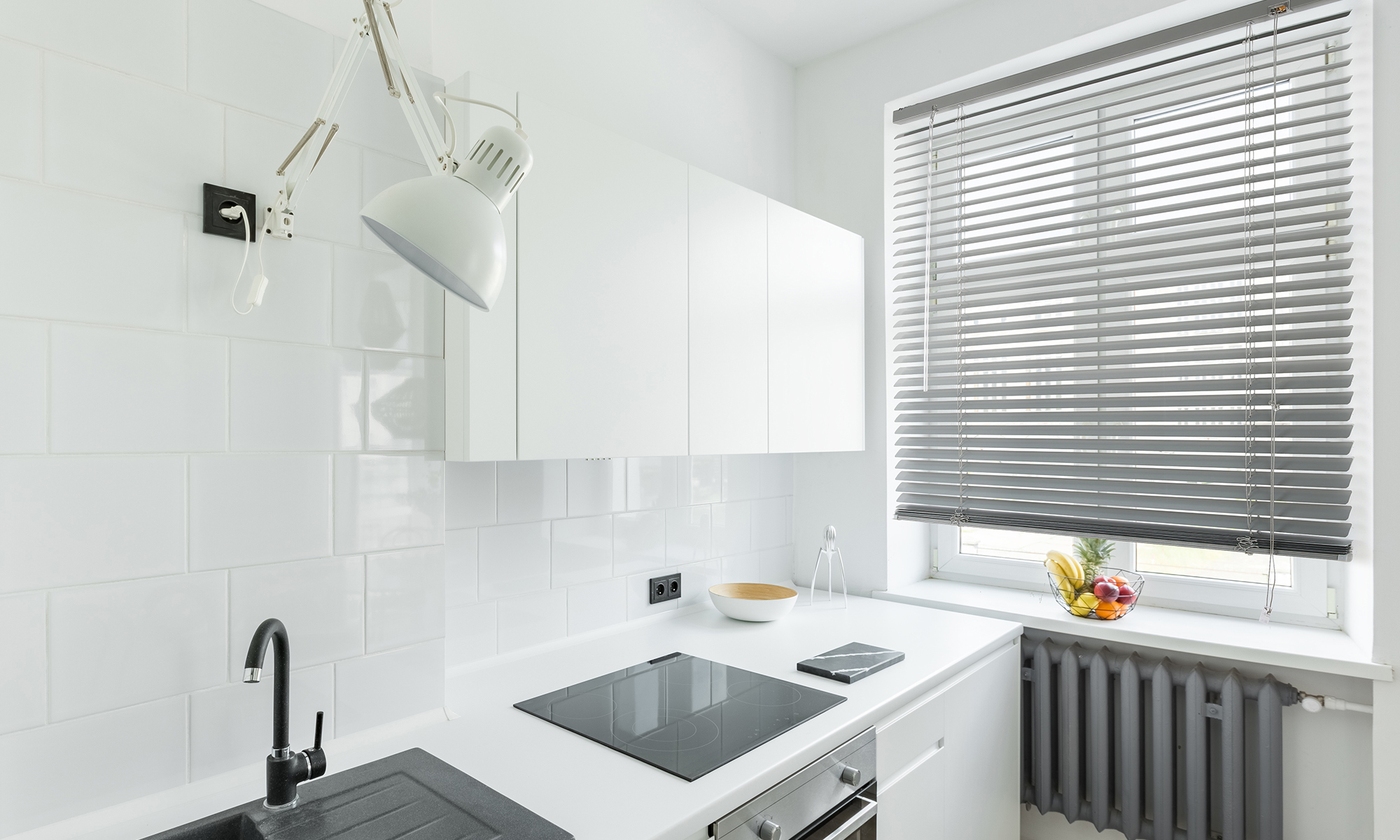 Aluminium Jalousie an einem Fenster in einer modernen Küche mit weißen Schränken und Geräten