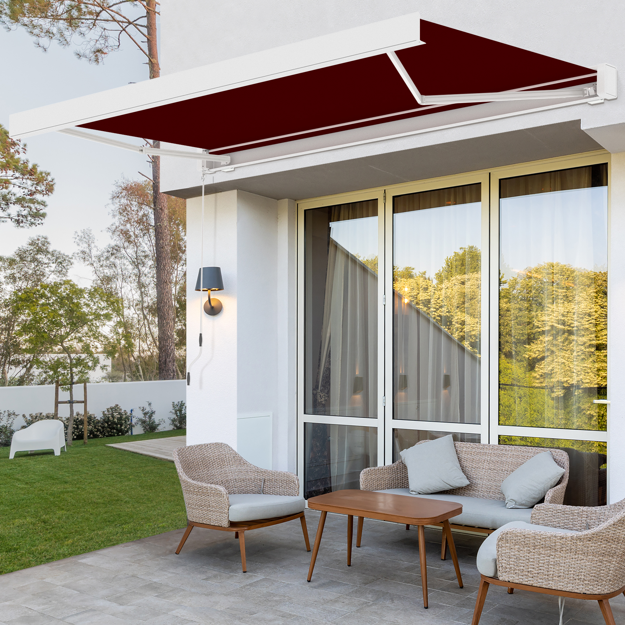 Kassettenmarkise mit LED-Beleuchtung über Terrasse mit Sitzgruppe und Garten im Hintergrund