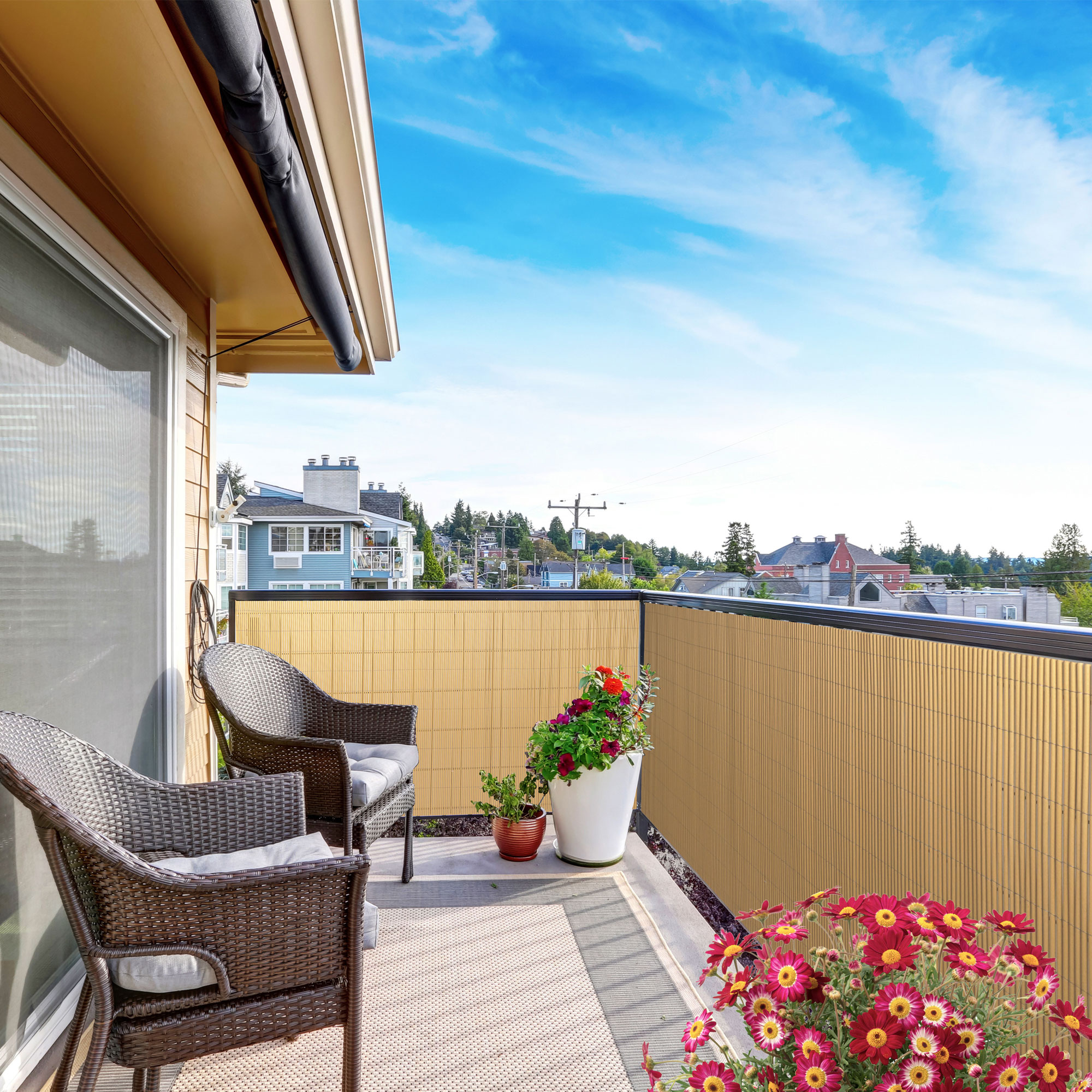 Balkon mit Sichtschutzmatte und Abdeckprofil, zwei Stühle, Pflanzen, Ausblick auf Häuser und Bäume
