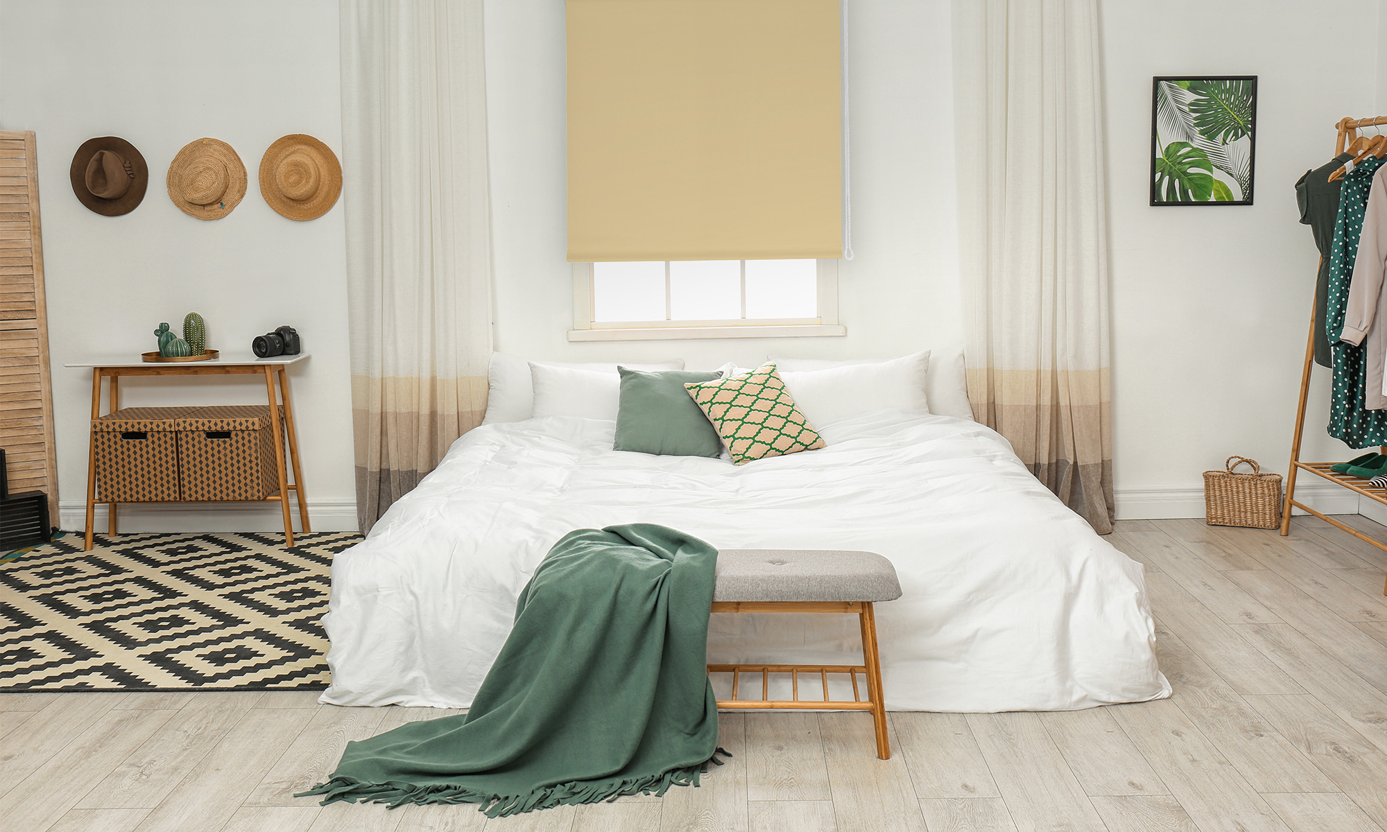 Schlafzimmer mit Bett, Rollos am Fenster, Kleiderständer, Dekoration und Teppich