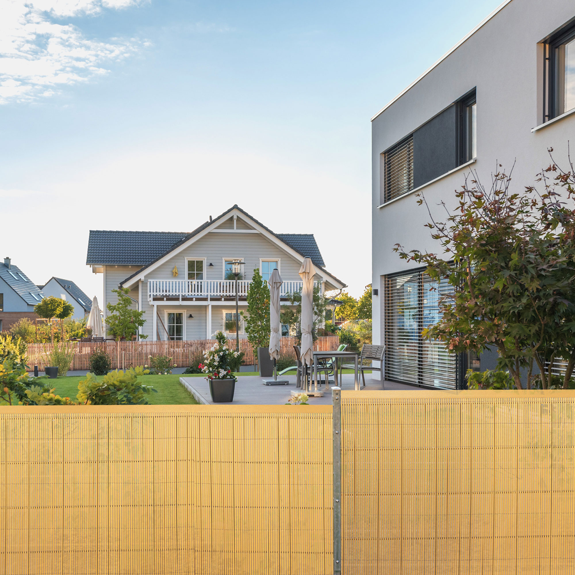 Abdeckprofil für Sichtschutzmatte vor modernem Haus und Garten im Hintergrund