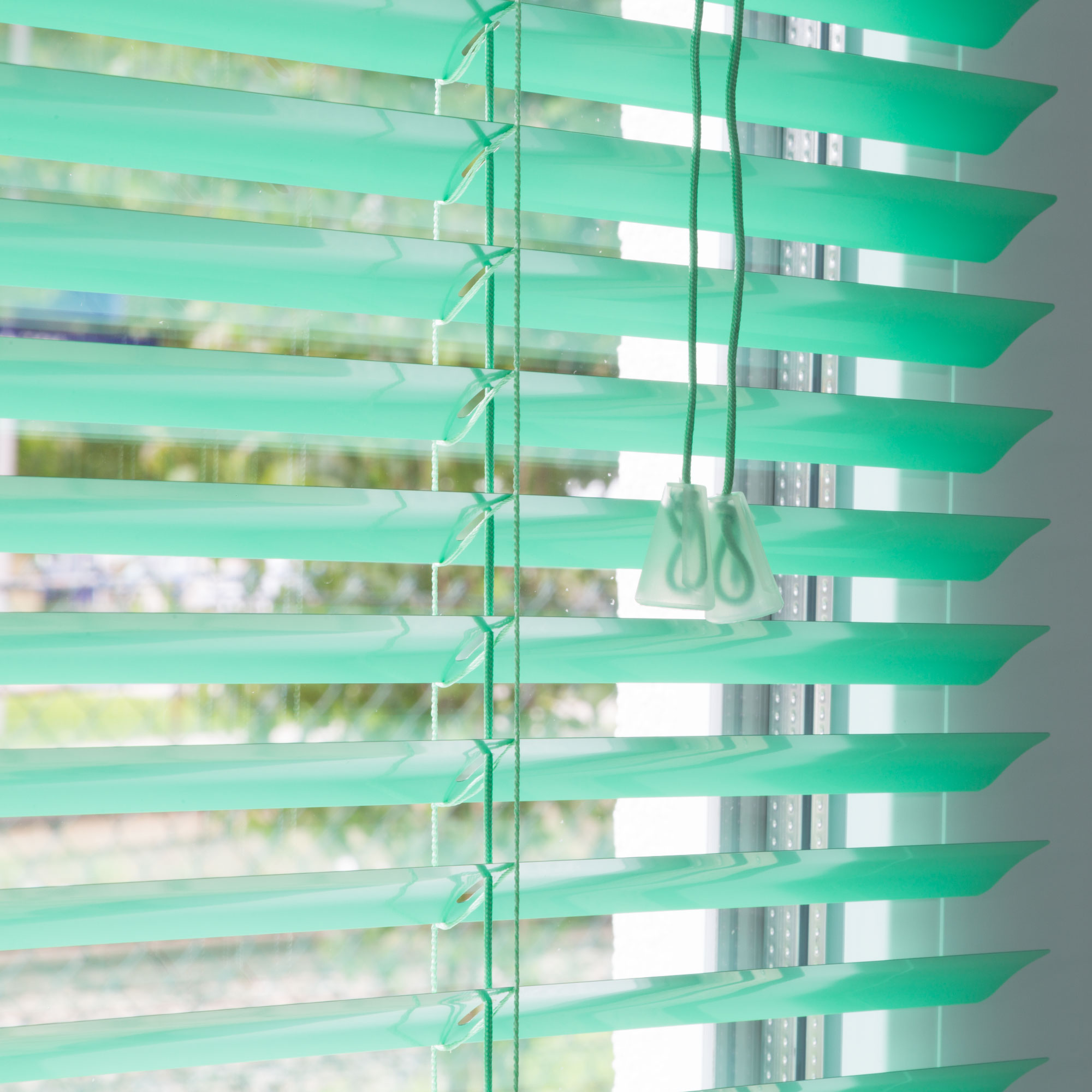 Aluminium Jalousie mit Lamellen und Zugkordel vor einem Fenster
