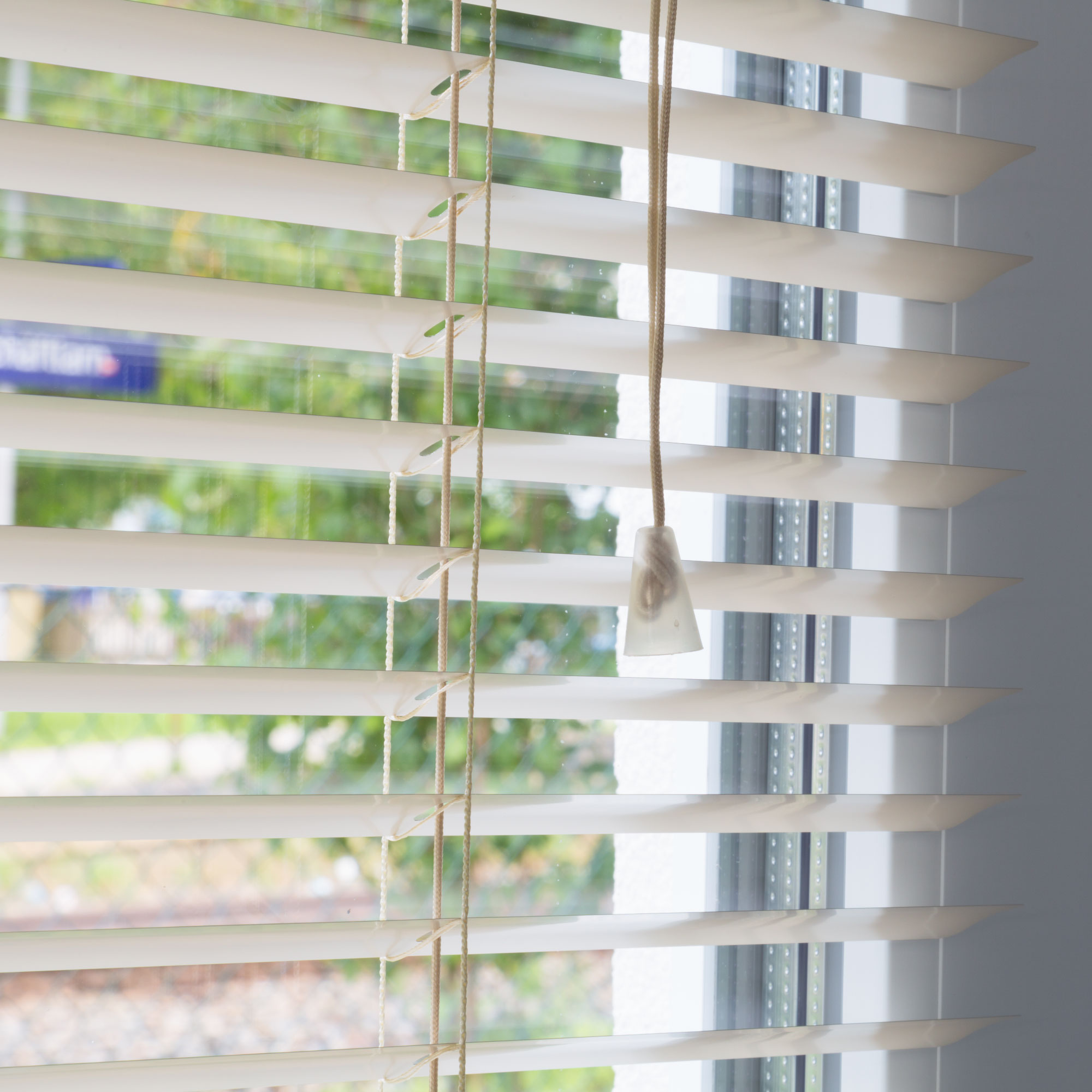 Aluminium Jalousie mit Lamellen und Zugkordel vor einem Fenster