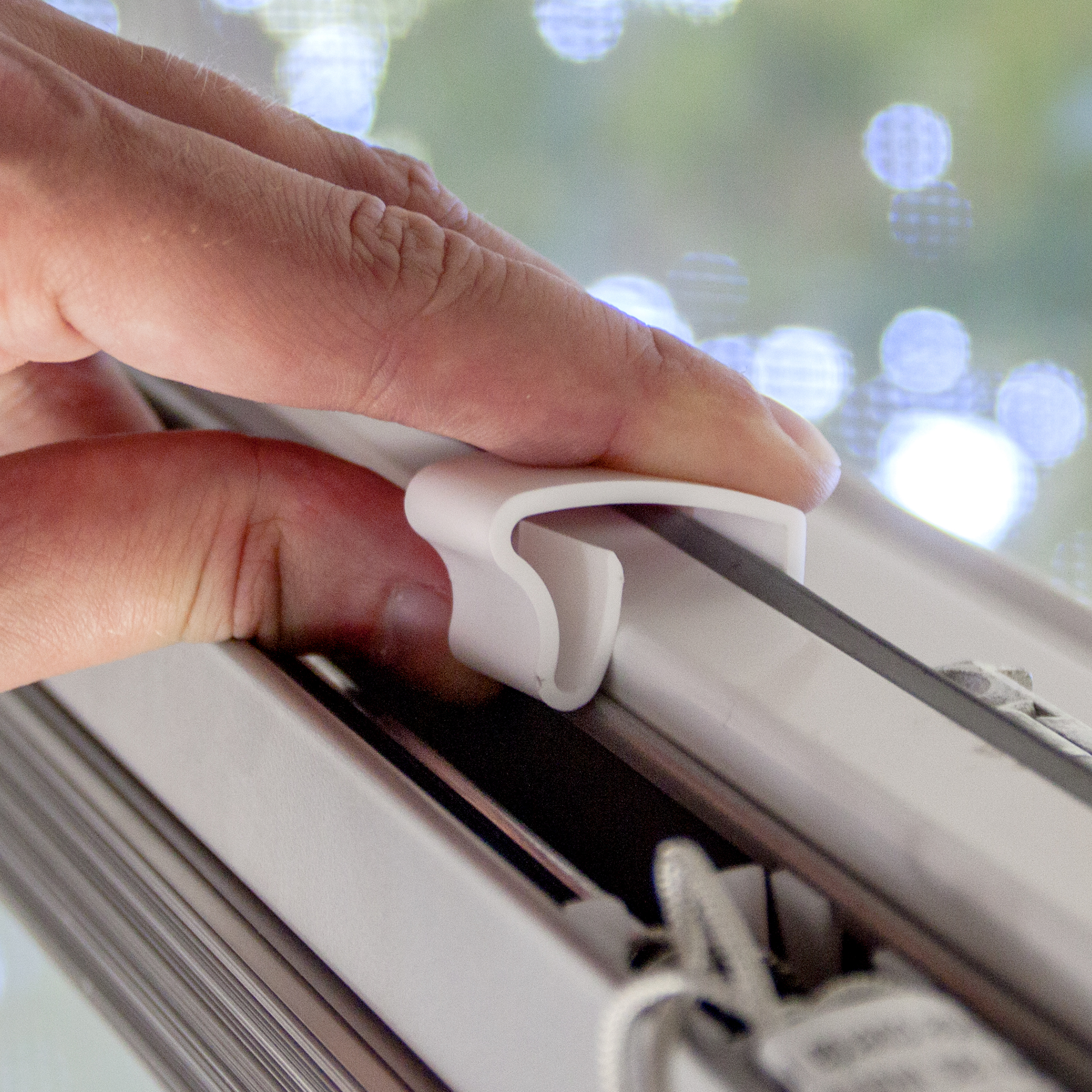 Hand befestigt einen Clip an einer Schiene eines Fenstersystems