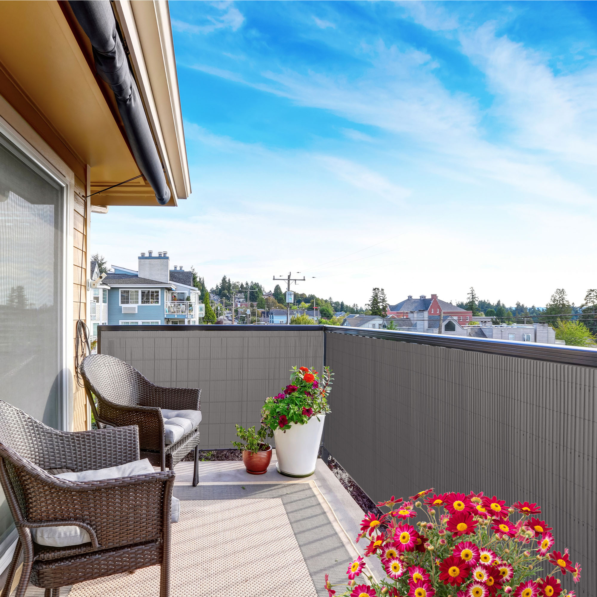 Balkon mit Sichtschutzmatte und Abdeckprofil, zwei Stühle, Pflanzen, Ausblick auf Häuser und Bäume